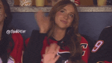 a woman wearing a number 9 jersey applauds