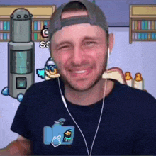 a man wearing headphones and a baseball cap is smiling in front of a video game .