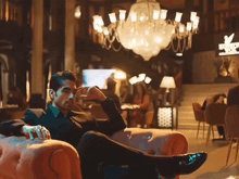 a man in a suit sits on a chair with his feet up