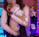 a woman is holding a brown and white dog in her arms in front of a microphone .