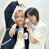 two young men are standing next to each other making a heart shape with their hands .