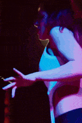 a woman is dancing in a dark room with a blue light behind her
