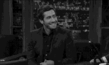 a black and white photo of a man in a suit laughing on a show .