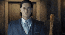 a man in a suit and tie is standing in front of a door in a room .