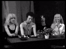a black and white photo of a group of people sitting around a table