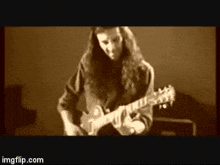 a man with long hair is playing an electric guitar in a sepia tone .