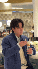 a man in a blue jacket is eating ice cream from a cone