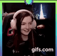 a woman wearing headphones is smiling while sitting in a chair in front of a computer .