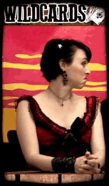 a woman in a red dress sits in front of a wildcards poster