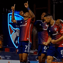a group of soccer players are celebrating a goal and one of them has the number 7 on his jersey