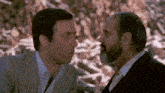two men are looking at each other and one has a beard