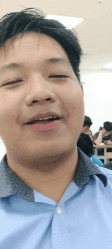 a man in a blue shirt is smiling and looking at the camera