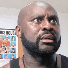 a bald man with a beard is looking at the camera in front of a poster that says house