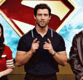 a man in a blue shirt stands in front of a superman symbol