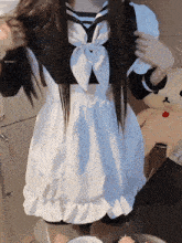 a girl in a maid costume is standing next to a stuffed animal
