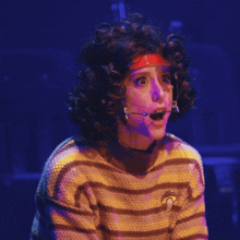 a woman wearing a striped sweater with a mushroom embroidered on it