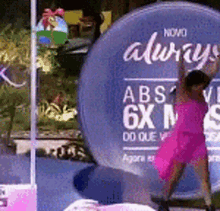 a girl in a pink dress is standing in front of a sign that says always