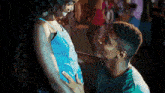 a man kissing a woman 's belly in a crowded area