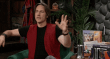 a man in a red vest is sitting in front of a daggerheart game