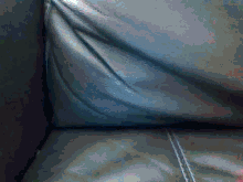 a close up of a blue leather couch with a stitched corner