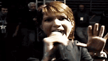 a woman singing into a microphone while wearing a black shirt with a star on the front