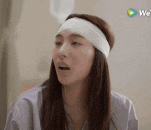 a woman with a bandage on her head is sitting in a hospital bed