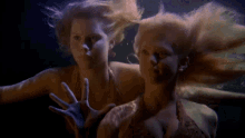 two mermaids are swimming in the dark water