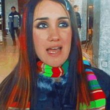 a woman with long hair and a scarf around her neck is smiling