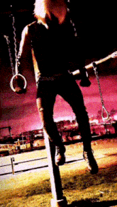a person is hanging from a pole with rings around their arms