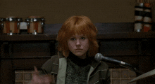 a woman with red hair is singing into a microphone in front of a sign that says ami on it