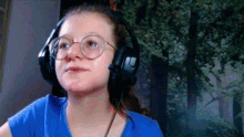 a girl wearing glasses and headphones is looking at the camera