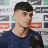a man in a blue shirt is talking into a microphone in front of a sign that says laliga