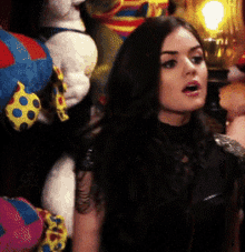a woman stands in front of a bunch of stuffed animals including a clown