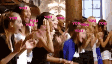 a group of women are clapping in a room with the word you written in pink