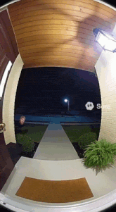 a man stands in the doorway of a house at night with a smiley face on the screen