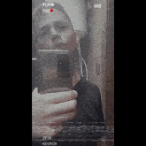 a young man is taking a selfie in front of a vhs tape player