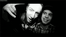 two men are posing for a selfie in a black and white photo .