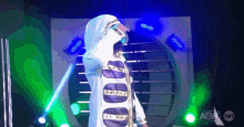 a person in a white hooded jacket stands in front of a sign that says aew on it