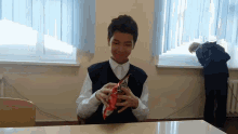 a boy is sitting at a desk holding a bag of fritos