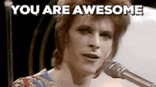 a man singing into a microphone with the words " you are awesome " written above him