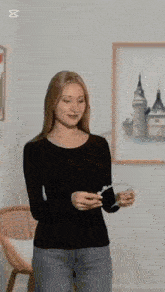 a woman in a black shirt is standing in front of a framed picture of a castle .