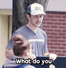 a man wearing a baseball cap and a shirt that says absolutores is talking to a girl
