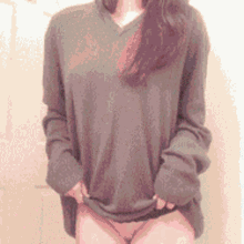 a woman wearing a green sweater and thong is taking off her shirt