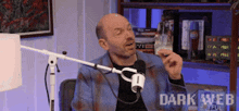 a man is sitting in front of a microphone with dark web written on the bottom of the screen
