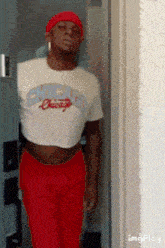 a man wearing a chicago crop top and red pants is standing in a doorway .