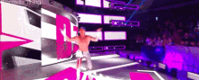 a wrestler is standing on a stage in front of a large screen with the number 1 on it .