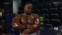 a shirtless wrestler is standing in a stadium with his arms crossed