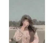a woman covering her face with her hand while standing in a field .