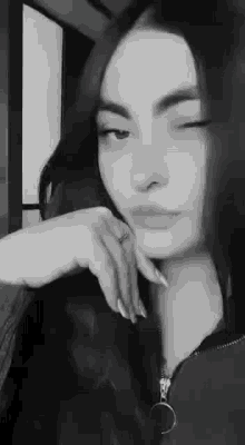 a black and white photo of a woman with long hair looking at the camera .