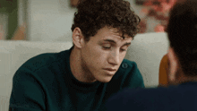 a man with curly hair is looking down at something